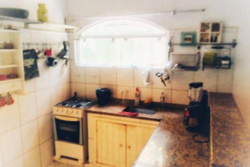a small kitchen with a stove and a window at Canto sossego casa independente a passos do mar in Búzios