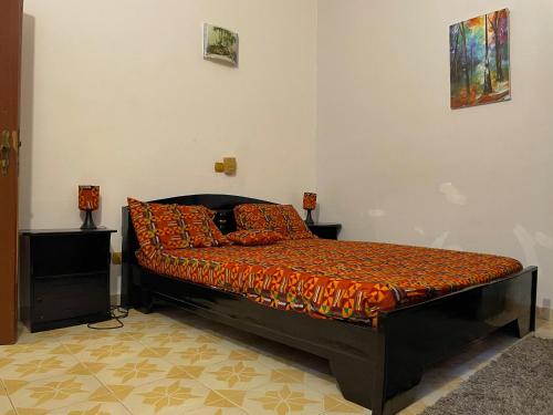 ein Schlafzimmer mit einem Bett mit orangefarbener Bettwäsche und Kissen in der Unterkunft Sylvadore'Appart in Cotonou
