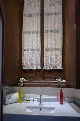 a bathroom sink with a window with two bottles on it at Hotel Gertrudis in Morelia