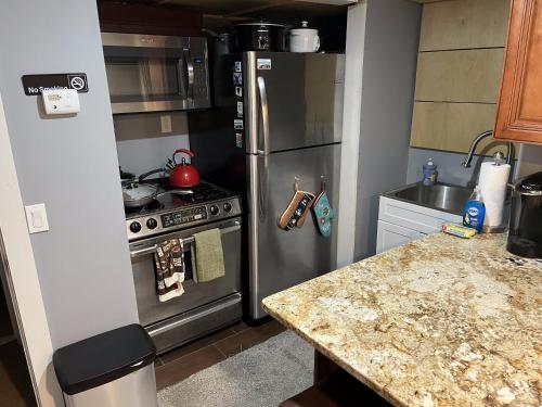 uma cozinha com um frigorífico de aço inoxidável e um fogão em Plush garden level apartment near Stowe em Morristown