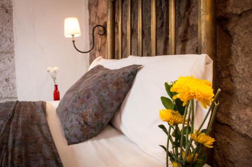 a bed with a pillow and a vase of yellow flowers at Hotel Gertrudis in Morelia