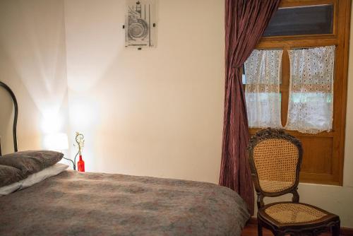 a bedroom with a bed and a chair and a window at Hotel Gertrudis in Morelia