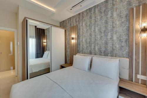 a bedroom with a large white bed and a mirror at Kusadasi Seasight in Kuşadası