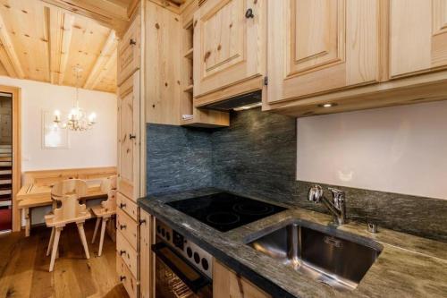 a kitchen with wooden cabinets and a sink and a table at Unterkunft CASA LA RODA NR 5 URSIN in Sedrun