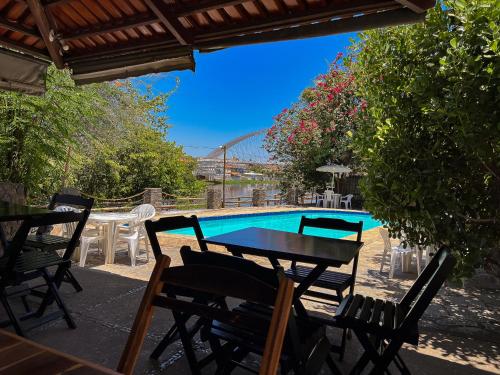 d'une terrasse avec une table et des chaises à côté de la piscine. dans l'établissement Pousada do Rio Corrente, à Santa Maria da Vitória