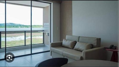 a living room with a couch and a large window at Prive Praias do Lago Ecoresort in Caldas Novas