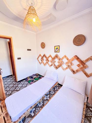 a room with two beds and a chandelier at Boilers Surf House in Tamri