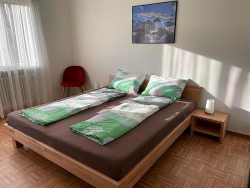 een bed met groene lakens en een rode stoel in een kamer bij DaSaNa Wohnung in Gordola