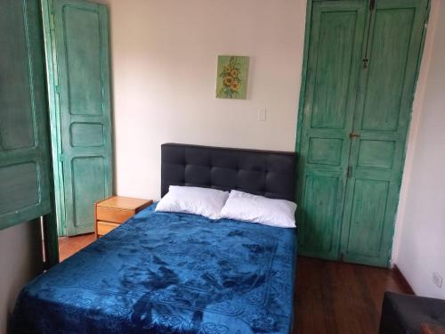 a bedroom with a bed and two green doors at MAMBE HOSTEL in Bogotá