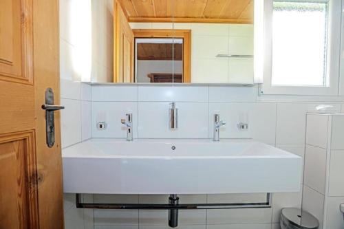 a bathroom with a white sink and a window at Casa La Roda Nr 3 in Sedrun