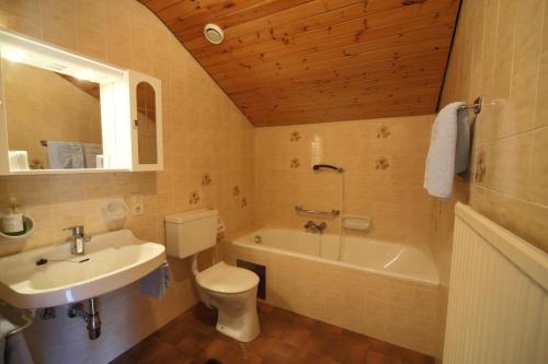 łazienka z umywalką, toaletą i wanną w obiekcie Gästehaus Lienharterhof w mieście Obertilliach