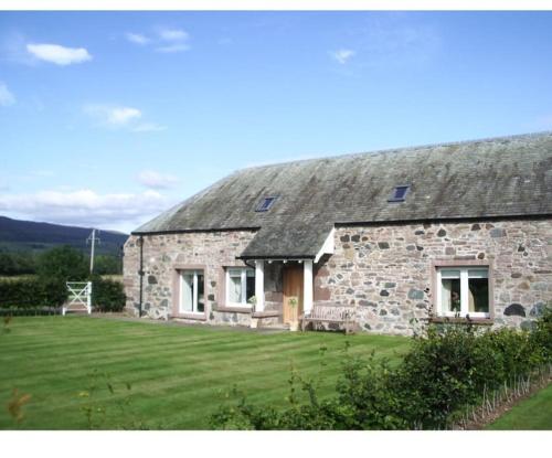 a stone house with a grassy yard in front of it at Fairness Cottage, Near Comrie in Comrie