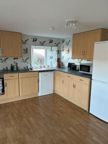 a kitchen with wooden cabinets and a white refrigerator at Fairness Cottage, Near Comrie in Comrie