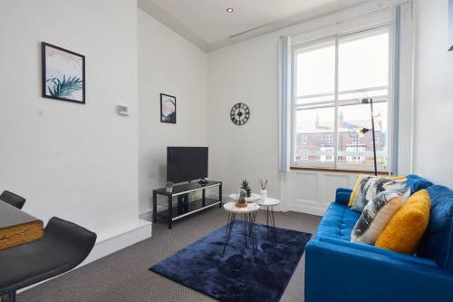 ein Wohnzimmer mit einem blauen Sofa und einem TV in der Unterkunft Stylish 2 Bed Apt in Leeds Centre - FREE Parking! Contact us for Better Offers! in Leeds