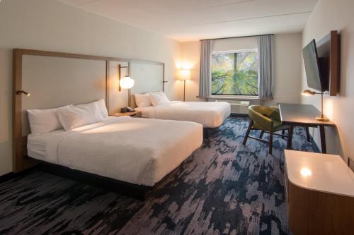 a hotel room with two beds and a desk at Fairfield Inn & Suites by Marriott Nashville Airport in Nashville