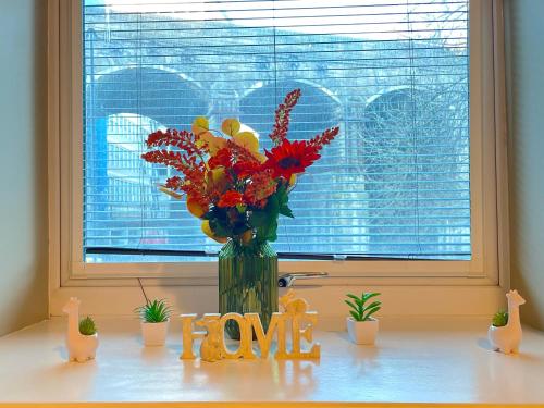 un jarrón lleno de flores sentado en una mesa con una ventana en HNFC Stays - Corporate Central Studios + Parking, en Newcastle