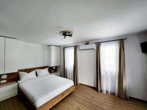 een slaapkamer met een wit bed en een raam bij Cozy house Elena in Drăgoiasa