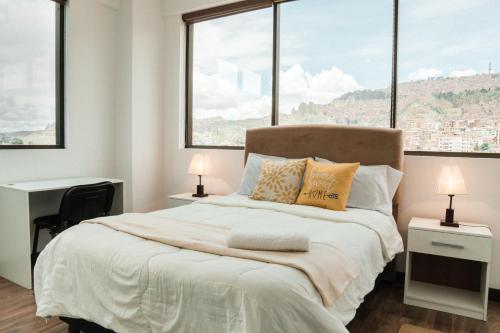 拉巴斯Sky Suites - Stunning Location with a great view of La Paz的一间卧室设有一张大床和两个窗户