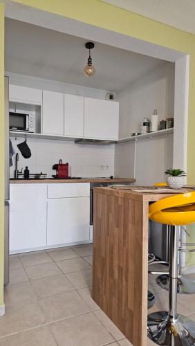 une cuisine avec des placards blancs et un tabouret jaune dans l'établissement Bel appartement F3 tout confort, à Saint-Vincent-de-Paul