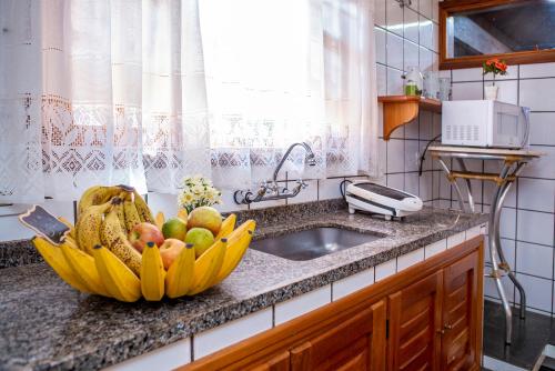a bowl of fruit on a counter next to a sink at Pousada Suiça Mineira Garden in Monte Verde