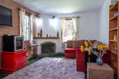 a living room with a red couch and a fireplace at Pousada Suiça Mineira Garden in Monte Verde