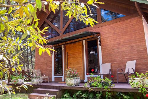 a house with a wooden porch with chairs and flowers at Pousada Suiça Mineira Garden in Monte Verde