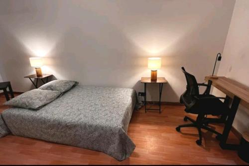 Un dormitorio con una cama, un escritorio y una silla. en Très beau 2 pièces à 400m de Paris, en Gentilly
