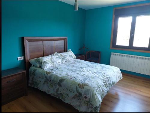 a bedroom with a bed and a blue wall at Apartamento Quinfon in Maceda