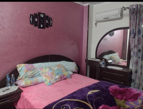 a pink bedroom with a bed and a mirror at شقه قريبه من الاهرامات والمتحف in Cairo