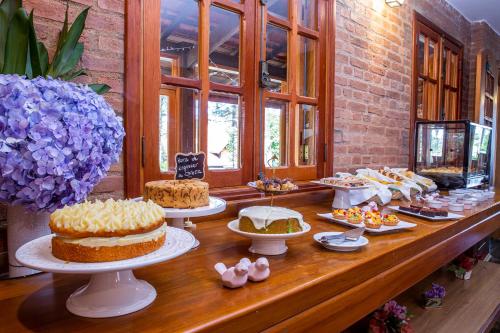 a buffet with cakes and other desserts on display at Pousada Suiça Mineira Garden in Monte Verde
