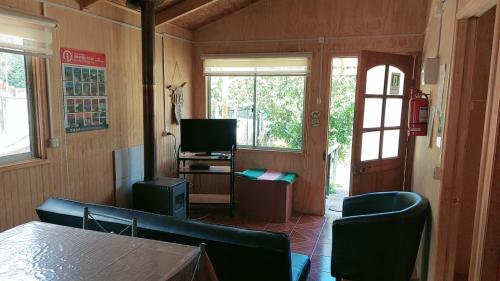 sala de estar con sofá, mesa y ventanas en Cabañas Kela, en Bahía Murta