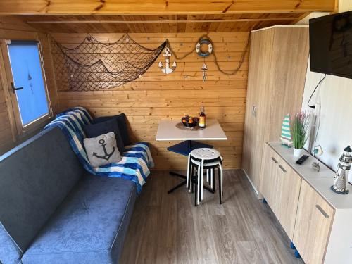 a tiny house with a couch and a table at Swojskie Chatki - Marynarska Chatka in Smołdziński Las