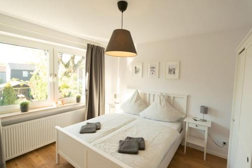 biała sypialnia z białym łóżkiem i oknem w obiekcie Moderne 2 Zimmer Wohnung (52qm) am CentrO! w mieście Oberhausen