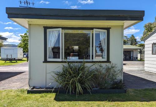 a small house with a window on the grass at Holdens Bay Holiday Park in Rotorua