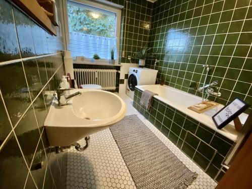 a green tiled bathroom with a sink and a tub at KU-02RI Apartment in Kulmbach OG in Kulmbach