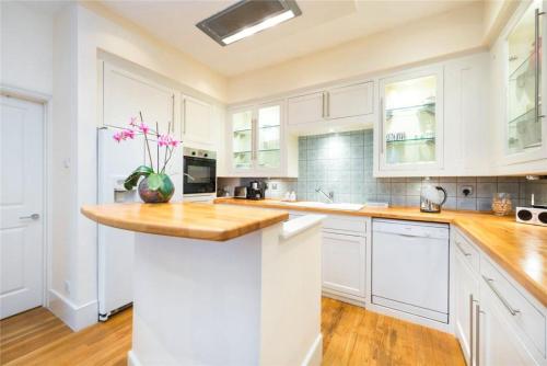a kitchen with white cabinets and a wooden counter top at Neat, bright, and convenient. in London