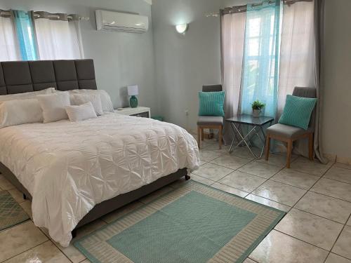 Savaneta的住宿－La Villas at Pos Chiquito Caribbean Paradise in Aruba，一间卧室配有一张大床和两把椅子