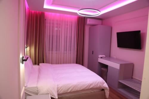 a pink bedroom with a bed and a television at Sky View Hotel & Restaurant in Kukës