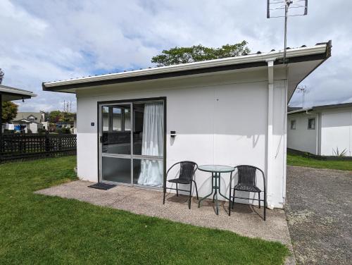 a small white house with a table and two chairs at Holdens Bay Holiday Park in Rotorua