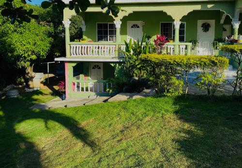 une maison verte avec un balcon blanc dans la cour dans l'établissement Cindy's Garden Stay, à Ocho Rios