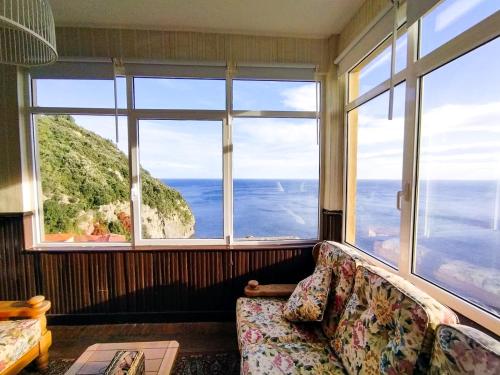 a living room with a couch and large windows at Mirando al mar, itxas gane in Elanchove