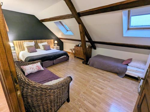 Marigny-lès-ReulléeにあるLa Clé des Champsの屋根裏のベッドルーム(ベッド2台、籐の椅子付)