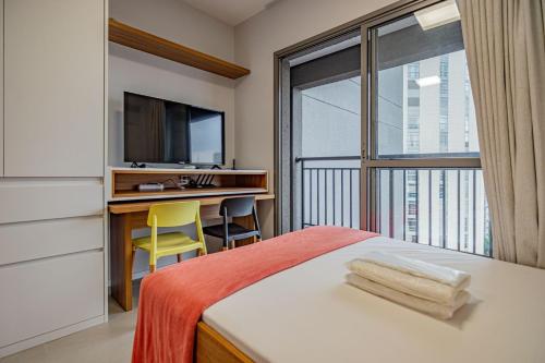a bedroom with a bed and a desk and a television at Piscina no Rooftop! Studio a 3min do Metrô República in São Paulo