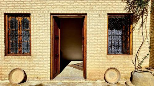 an open door of a brick building with two windows at Maison d'hôtes "Dar Khalifa" in Tozeur