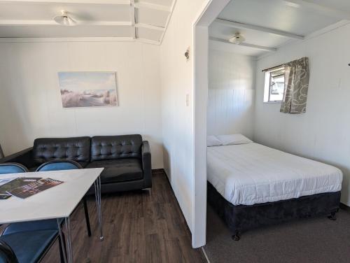 a small room with a bed and a couch at Holdens Bay Holiday Park in Rotorua