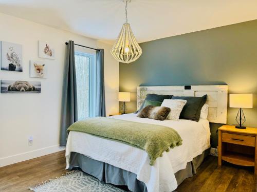 a bedroom with a large bed and a chandelier at Woodpecker Spa and peace in Orford