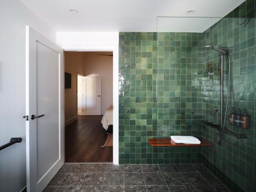 a bathroom with a shower and a green tile wall at Shawwood Estate in Mudgee