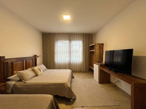 a hotel room with two beds and a flat screen tv at Pousada Pouso de Laura in Tiradentes