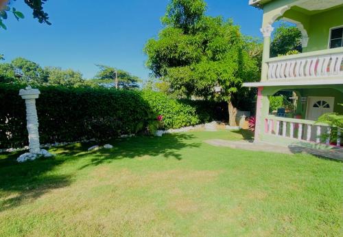 a house with a grass yard next to a building at Cindy's Garden Stay in Ocho Rios