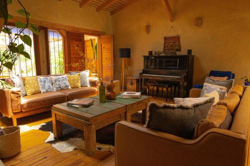 a living room with couches and a table and a piano at El EQUIMITE HOTEL BOUTIQUE in Coatepec